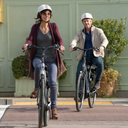 两个穿着随意的骑手，一男一女，在自行车道上骑着电动自行车。18luck新利娱乐在线